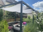 Vela ombreggiante impermeabile premium 3x4 m montata su una pergola in metallo sopra un set di mobili da giardino.