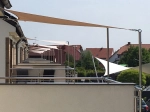 Velă solară bej impermeabilă premium 3x4 m montată pe terasa unei clădiri moderne.