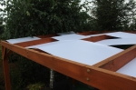 Bande d'ombrage blanche sur mesure pour belvédère, montée sur une structure de jardin en bois.