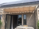 Wasserdichtes ausziehbares Sonnensegel 3x5 m in Beige, montiert über einer Terrasse eines Hauses mit Photovoltaikanlagen.