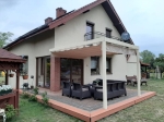 Horizontal premium Roman blind Decor 4x4 mounted on a white terrace pergola by a detached house.