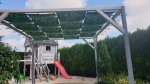 Grafische zonneschermstrook op maat voor prieel met bladmotief, gemonteerd op een houten pergola in de tuin.