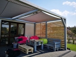 Custom-made waterproof sun sail installed over a terrace with pallet furniture and bean bags.