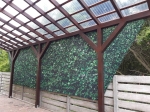 Фіранка на замовлення з принтом зеленого листя, встановлена під дерев'яним дахом на терасі.