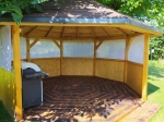 Maßgeschneiderter Vorhang mit Grafik in einem Holz-Gartenpavillon mit Grill auf einem gemusterten Boden.