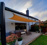 HDPE Sonnensegel 5x5 in Sandfarben montiert über einer Terrasse mit modernen Gartenmöbeln.