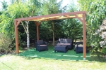Striscia parasole in HDPE giallo 0,5x5 m montata su una pergola in legno con mobili da giardino marroni.