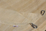 Voile d'ombrage beige HDPE 5x6 m à tissage dense, avec fixations métalliques visibles et logo.