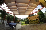 Οριζόντια premium ρωμαϊκή κουρτίνα Decor 2,5x3 m τοποθετημένη σε κατασκευή βεράντας πάνω από έπιπλα κήπου.