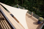 Vela de sombra premium impermeável 1,4x1,4x2 m bege, instalada sobre um terraço com deck compósito.