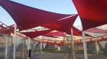 Vele ombreggianti impermeabili premium 1,4x1,4x2 m in rosso intenso montate sopra un passaggio.