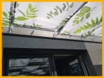 Voile d'ombrage de pergola sur mesure avec motif de feuilles, monté sur une structure de terrasse en bois.