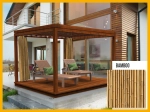 Terrassenvorhang mit Bambusmotiv auf einer modernen Pergola mit Liegestühlen vor dem Haus. Maßgeschneiderte Außengardine.