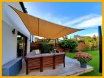Beige vierkant HDPE schaduwdoek 3x3 m gemonteerd boven een modern terras met tuinmeubilair.