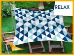 Waterproof sun sail 3x5 m with geometric blue patterns over a set of wooden garden furniture.