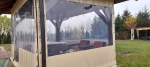 Custom-made transparent terrace cover with beige border, mounted on a wooden gazebo with furniture.