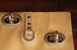 Terrace screen details: silver oval eyelets, turnbuckle fastener and mounting strap on beige material.