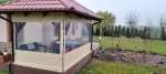 Husă de terasă la comandă cu fereastră din PVC montată pe foișor de lemn cu mobilier de grădină și jacuzzi.