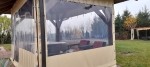 Maßgefertigte transparente Terrassenverkleidung mit beigem Rand, montiert an einer Holzlaube mit Möbeln.