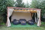 Tenda da giardino impermeabile su misura montata su un gazebo in legno con mobili in polirattan.