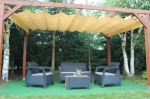 Bahçedeki ahşap pergola üzerine monte edilmiş yatay bej özel yapım HDPE Roma stor perde.