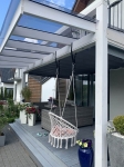 Tenda ombreggiante grigia su misura per giardino d'inverno montata sotto il tetto in vetro di una pergola moderna.