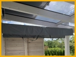 Toldo de sombra cinzento à medida instalado sob o telhado de vidro de um jardim de inverno numa estrutura branca.