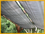 Uitschuifbaar HDPE-schaduwdoek op maat gemaakt, gemonteerd op een houten pergola in de tuin.