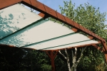 Toldo vela de HDPE blanco a medida montado en una pérgola de madera en el jardín.