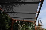 Op maat gemaakt HDPE schaduwdoek gemonteerd op een houten pergola in de tuin, beschermend tegen de zon.