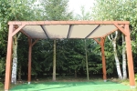 Vela de sombra clara em HDPE por medida instalada numa pérgola de madeira no jardim.