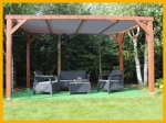 Wooden garden pergola with lounge furniture and custom-made HDPE sun sail in grey.