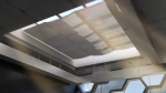 Custom-made internal fabric sunshade for a roof skylight in a modern glazed interior.