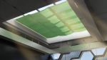 Green custom-made sunshade for roof skylight in a modern interior with glazing.