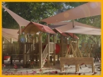 Wooden children's playground with custom-made sun sails on a sunny day.