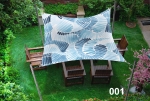 Waterdicht schaduwdoek 3x3 m met blauwe patronen, opgehangen boven houten stoelen op een groen gazon.