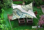 Voile d'ombrage carrée 3x3 m aux motifs de mosaïque verte, installée au-dessus de meubles de jardin en bois.