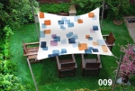 Voile d'ombrage imperméable 3x3 m aux carrés colorés, protégeant les meubles de jardin sur la pelouse. Produit 009.