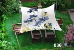 Voile d'ombrage imperméable 3x3 avec motif floral bleu, installée au-dessus de chaises en bois dans le jardin.