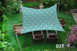 Square 3x3m sun sail in sea blue with a steering wheel motif over wooden garden furniture.