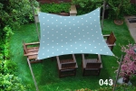 Waterproof garden sun sail 3x3 m polka dot pattern with garden furniture on green grass. Patio sun shade canopy.
