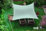 Waterproof garden sun sail 3x4 m with geometric pattern over wooden garden furniture.