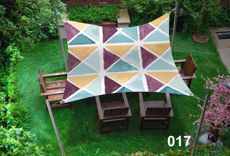 Vela de sombra retangular impermeável 3x5 m com padrão gráfico de triângulos coloridos sobre móveis de terraço.