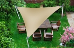 Vela de sombra triangular impermeable hecha a medida sobre un conjunto de comedor de madera en el jardín.