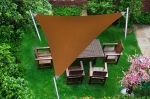 Toldo vela triangular marrón impermeable que cubre un conjunto de muebles de madera en el césped.