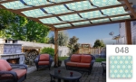 Zonwerende strook voor overkapping met geometrische patronen gemonteerd op een houten pergola boven een terras met meubels.