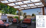 Zonneschermstrook voor overkapping met blauw plantenmotief, gemonteerd op een houten pergola boven een terras met meubels.