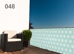 Custom-made balcony screen with geometric patterns 048 mounted on a terrace railing with a black armchair.