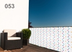 Custom-made colourful balcony screen with a small leaf pattern, mounted on a terrace railing with a dark armchair.