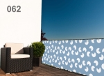 Lichtblauw balkon privacyscherm met wit patroon, gemonteerd op een terrasreling naast een zwarte fauteuil en een plant.